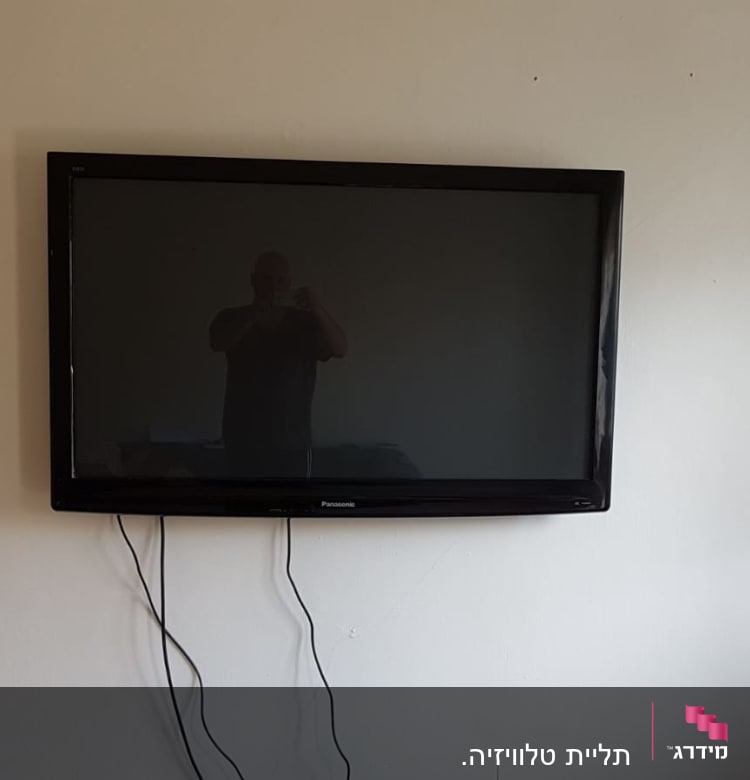 טלוויזיה תלויה על קיר עם כבלים חשמליים גלויים